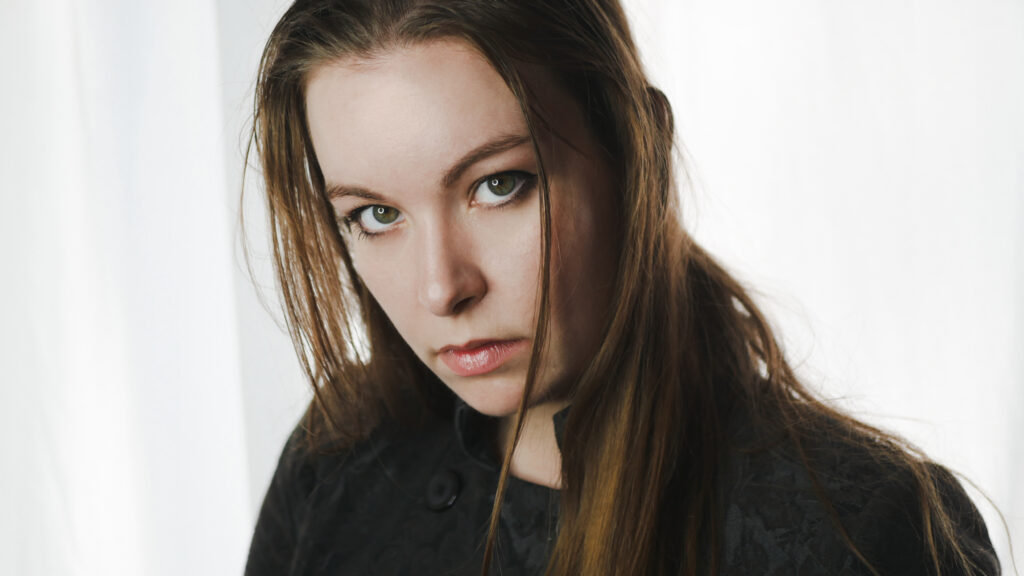 Portrait of singer Sofia Schmidt wearing a black jacket in front of a white background.